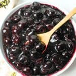 a bowl of sugar free cherry pie filling with a wooden spoon in it.