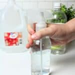 a hand holding a bottle of homemade window cleaner.