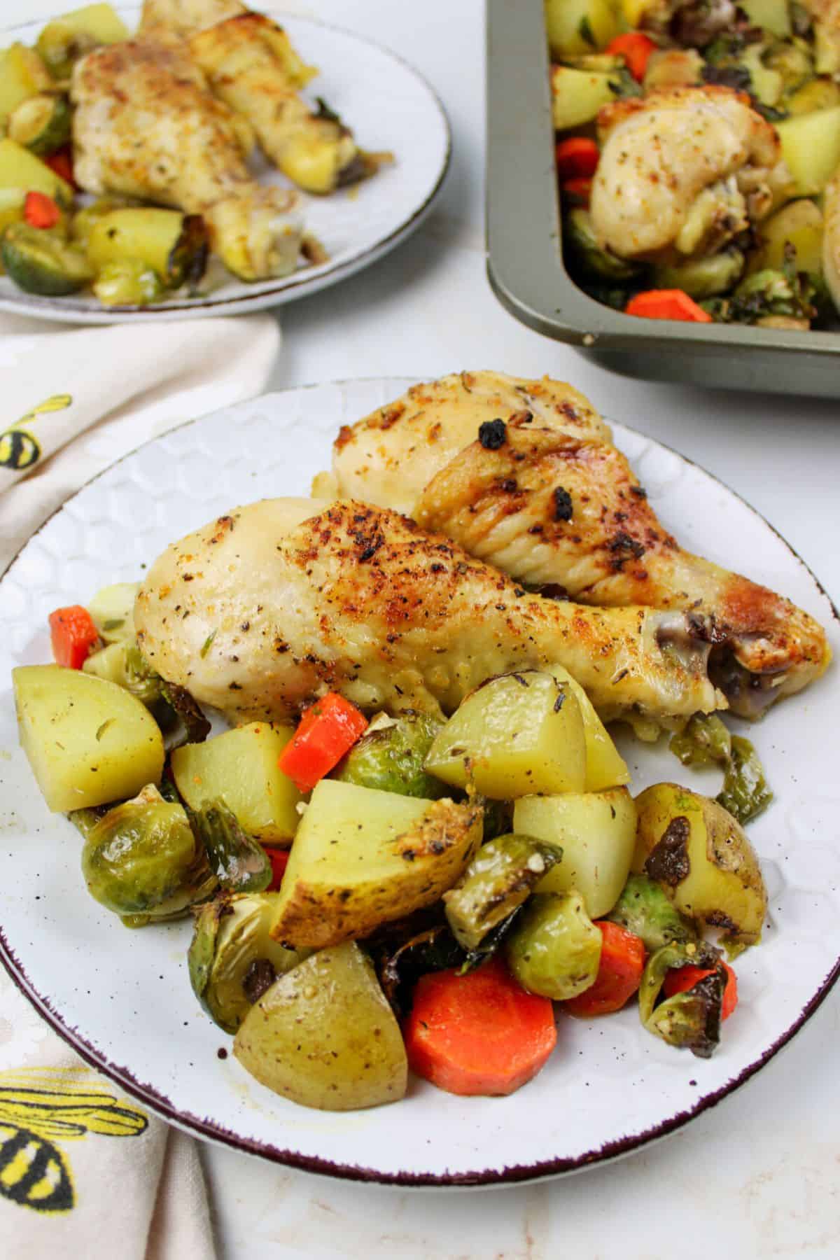 chicken legs, potatoes and veggies on plates.