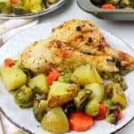 chicken legs, potatoes and veggies on a plate.