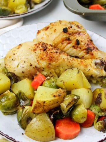 chicken legs, potatoes and veggies on a plate.