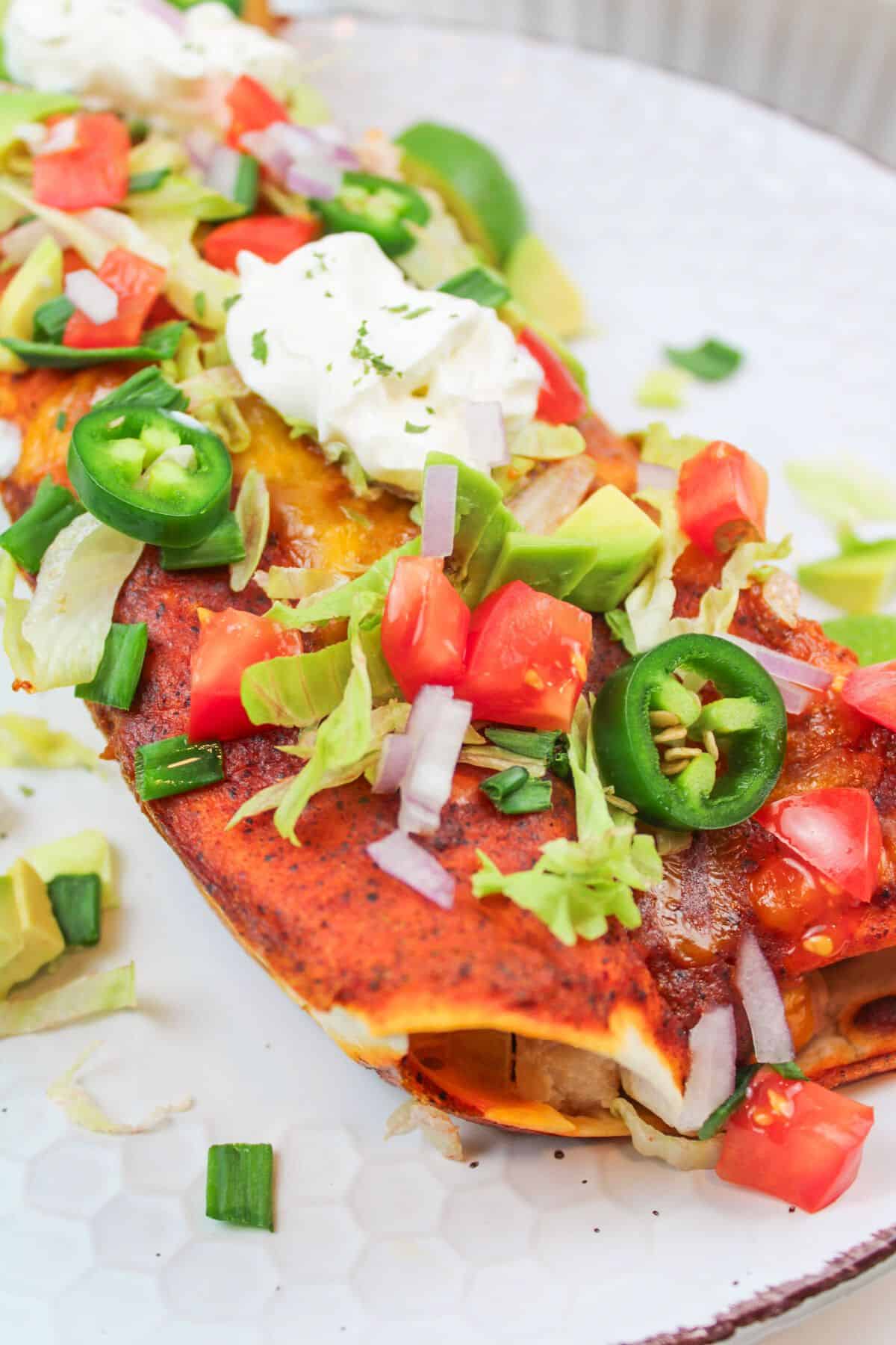 turkey enchiladas on a palte with toppings.
