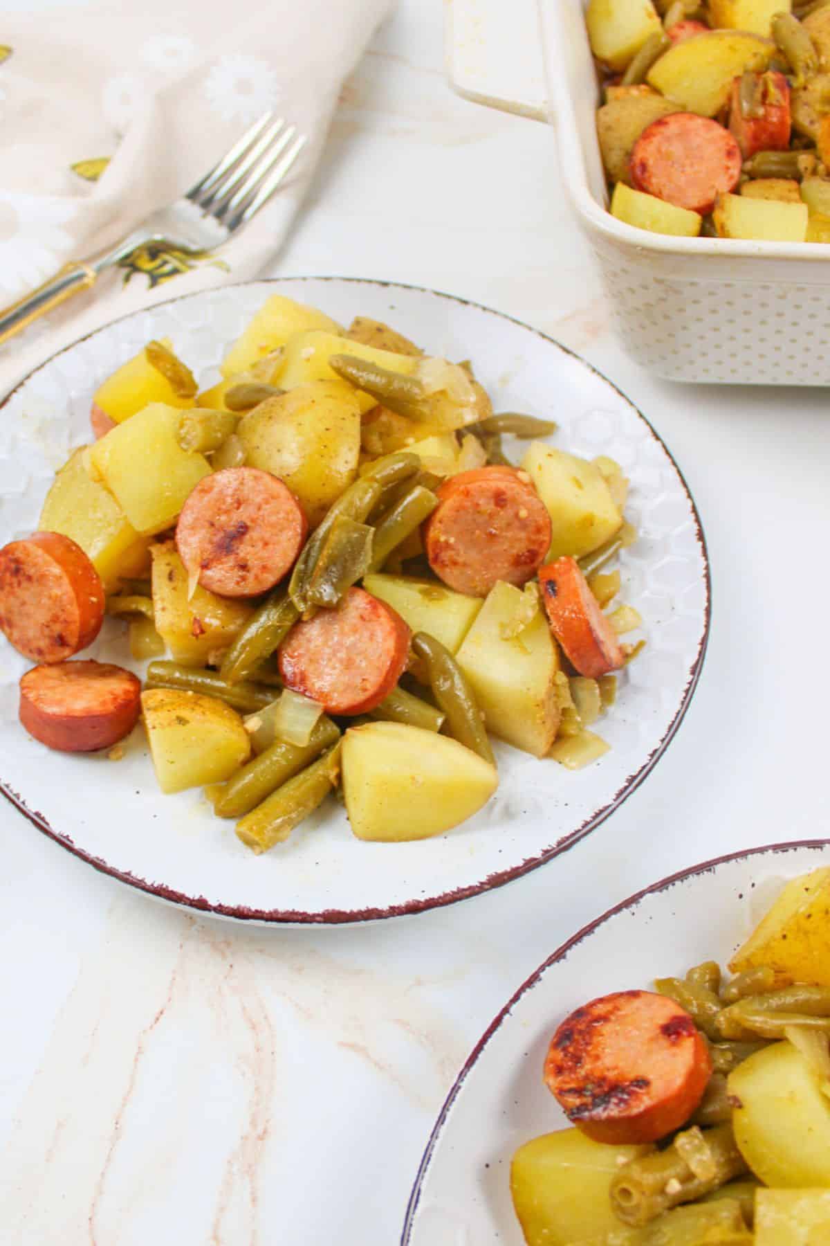 upclose angled view of sausage green bean potato casserole in a glass baking dish