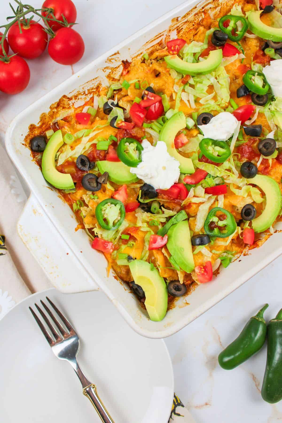 a walking taco casserole next to an empty plate with fork.