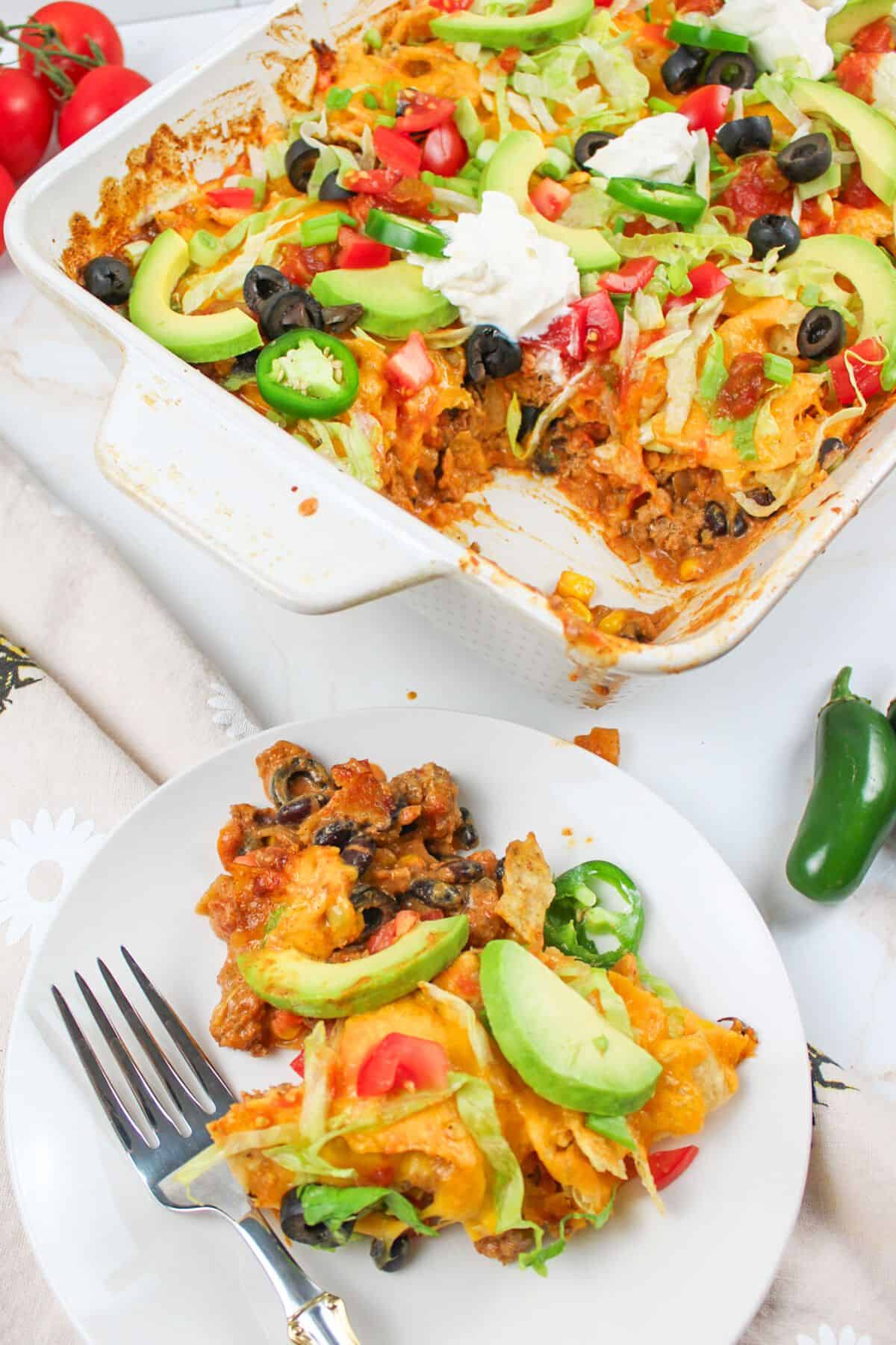 walking taco casserole in pan and served on plate with fork.