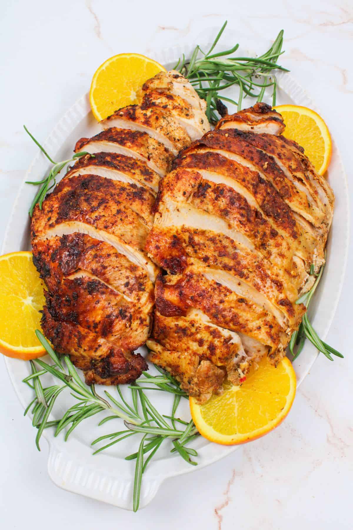 sliced cajun turkey breasts on a plate with garnishes.