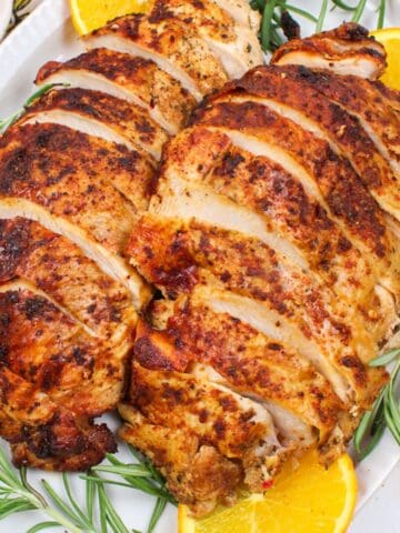 sliced cajun turkey breasts on a plate with garnishes.