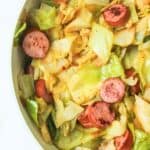 fried cabbage with sausage in a pan.