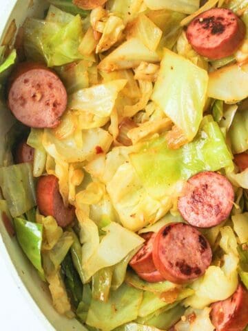 fried cabbage with sausage in a pan.