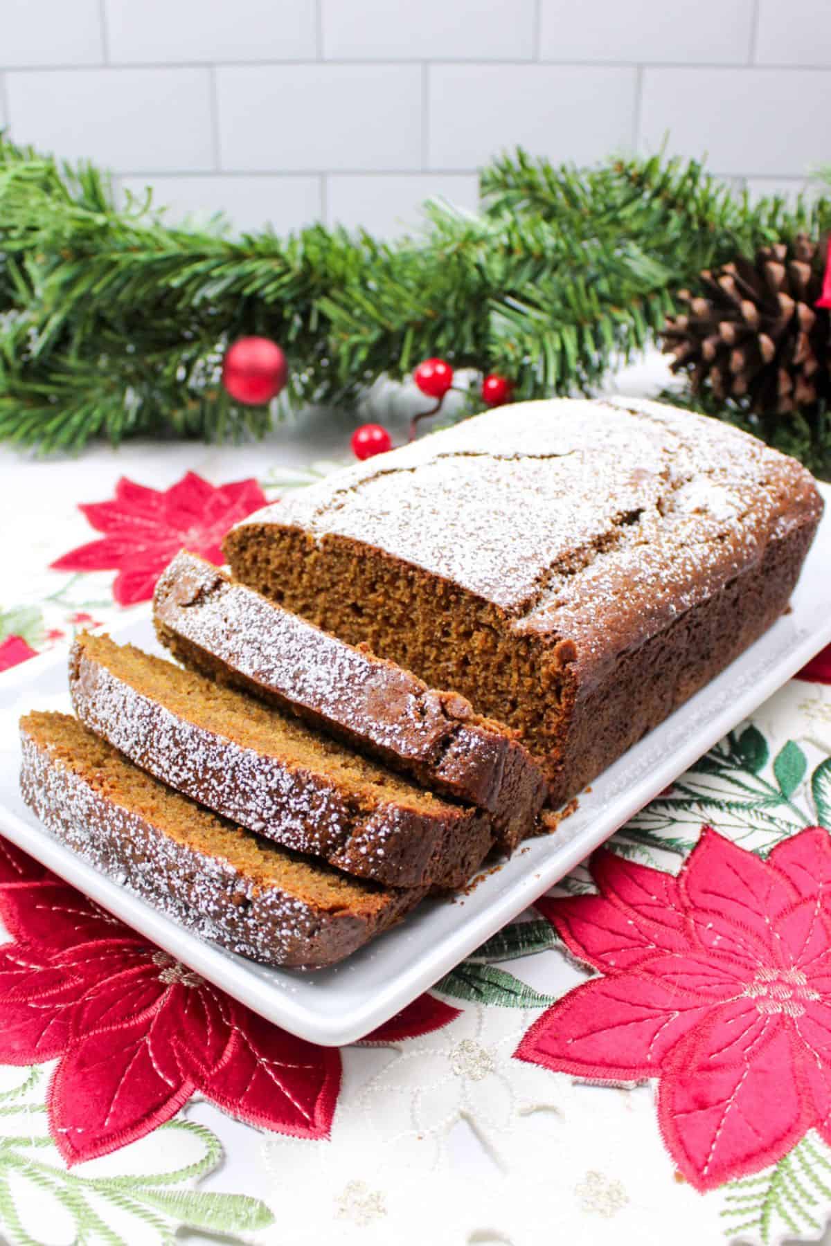 sliced gingerbread loaf on a plate topped with powdered sugar.