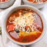 pizza soup topped with cheese in a bowl.