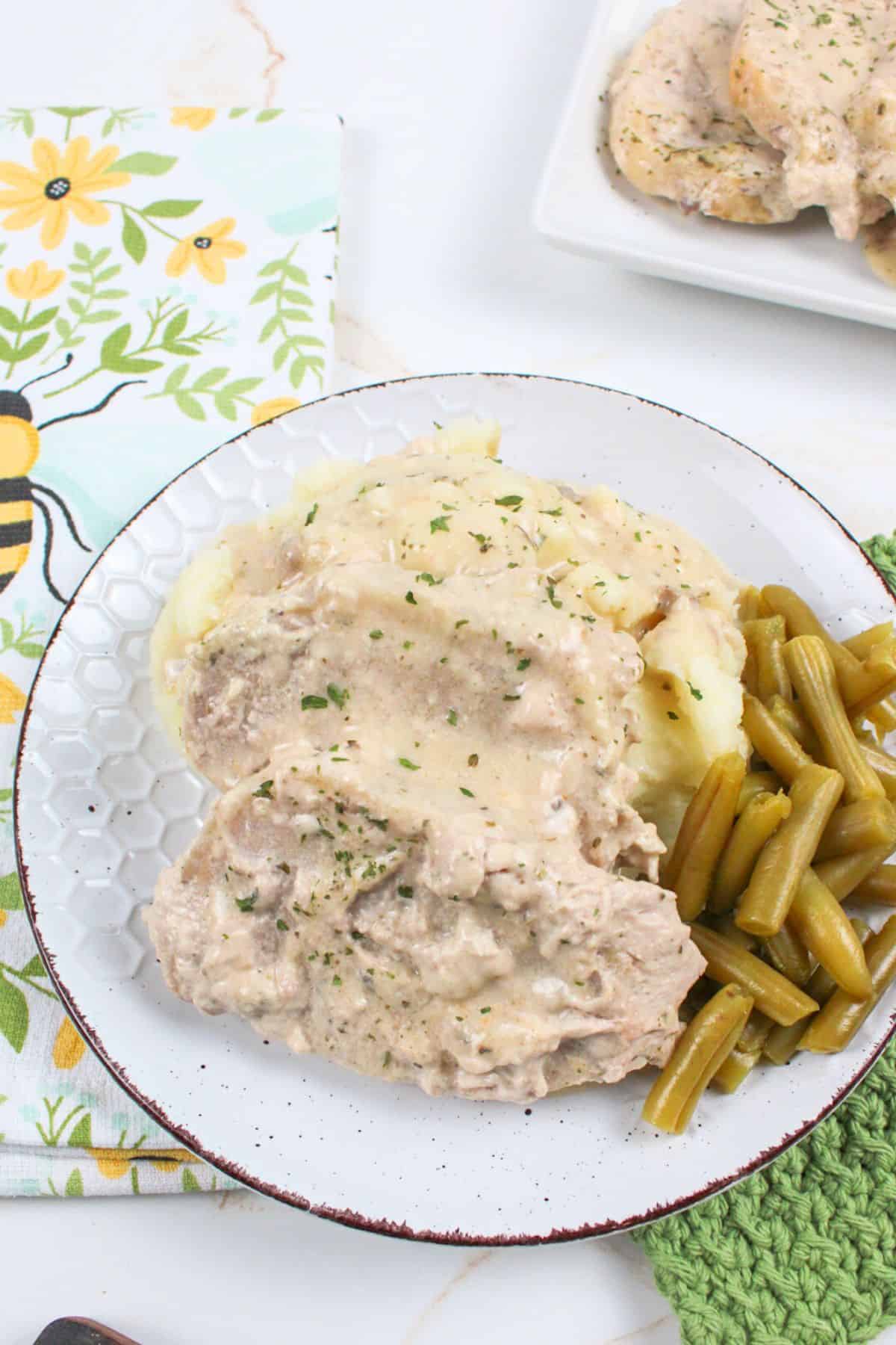 pork chops served on a plate with mashed potatoes and green beans.