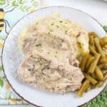 pork chops on a plate with mashed potatoes and green beans.