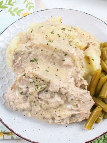 pork chops on a plate with mashed potatoes and green beans.