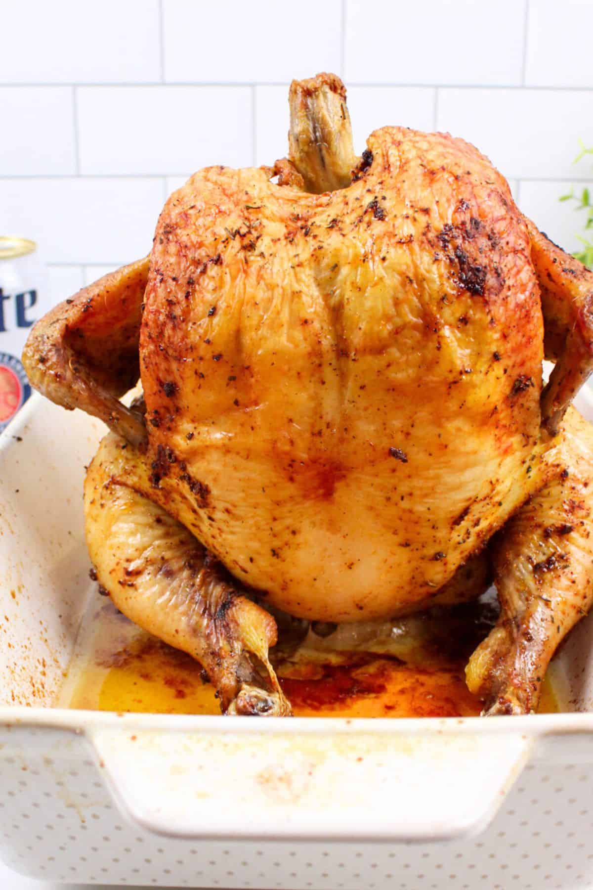 baked beer can chicken standing in a baking dish.