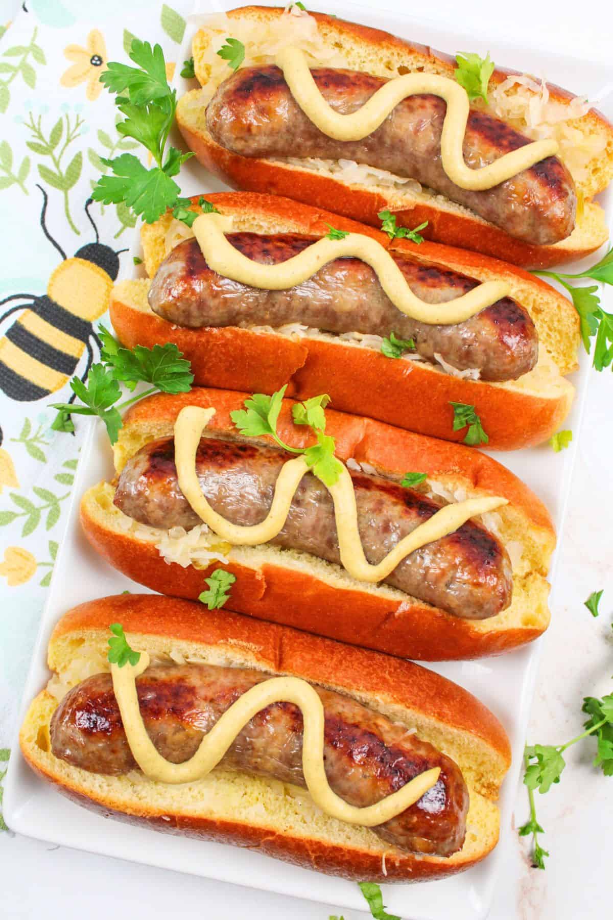 baked brats in buns with mustard on top.