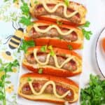 baked brats in buns with mustard.