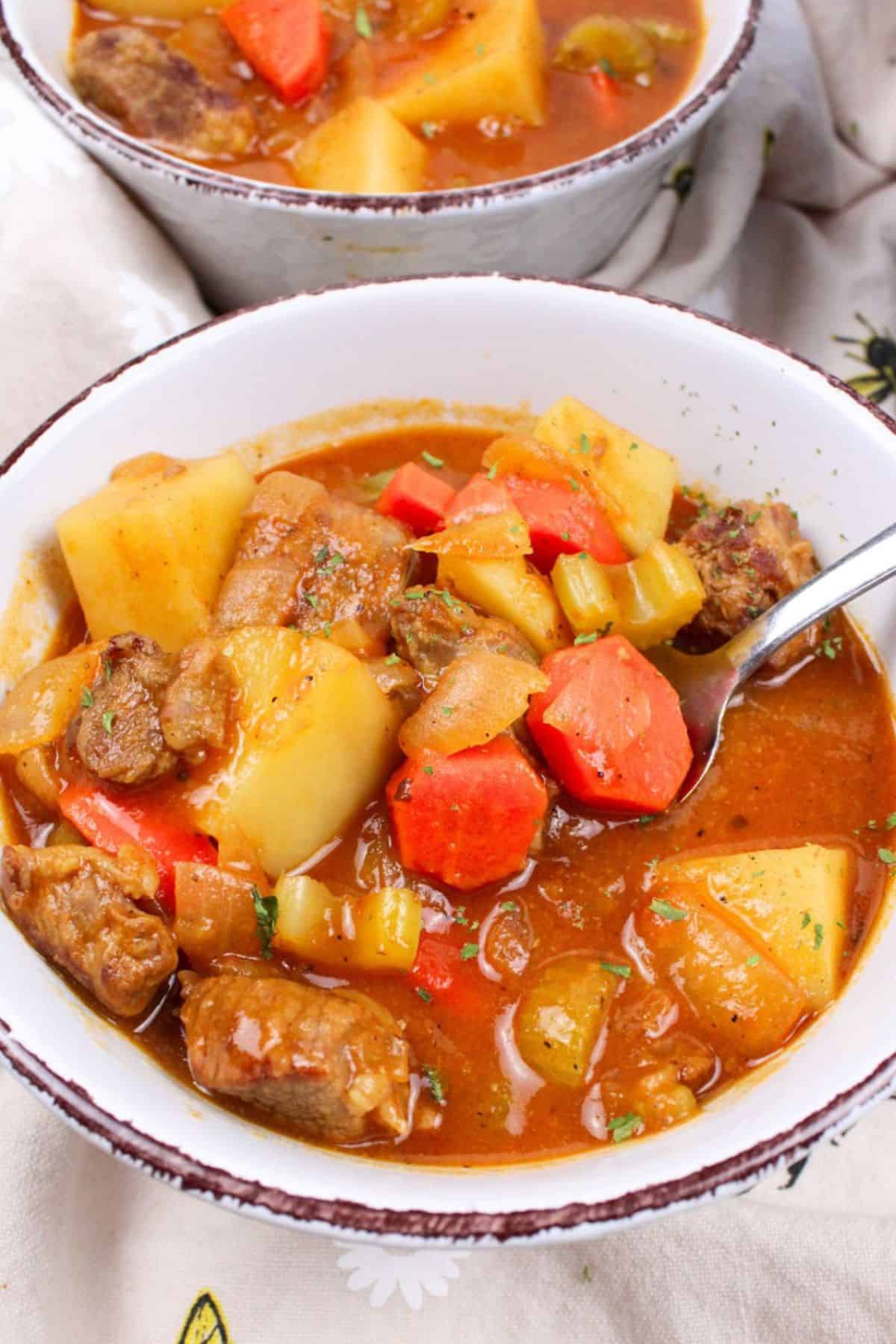 spoon full of beef stew in a bowl.