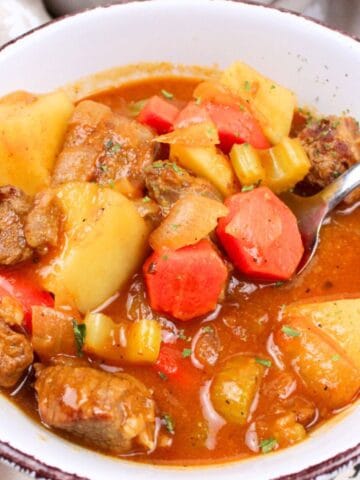 spoon full of beef stew in a bowl.